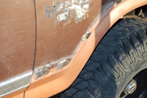 1982 Ford Bronco - A close-up view of a brown Ford Bronco fender shows areas of rust repair and a large off-road tire.