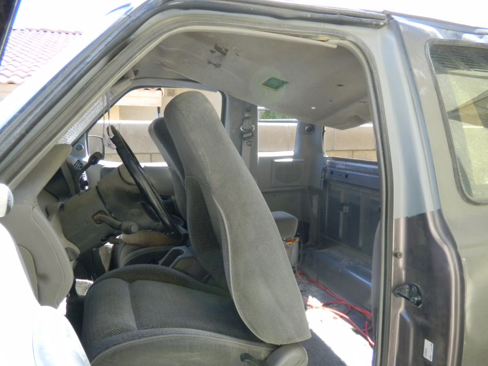 Gray interior of a 1997 Ford Ranger with cloth seats and exposed wiring