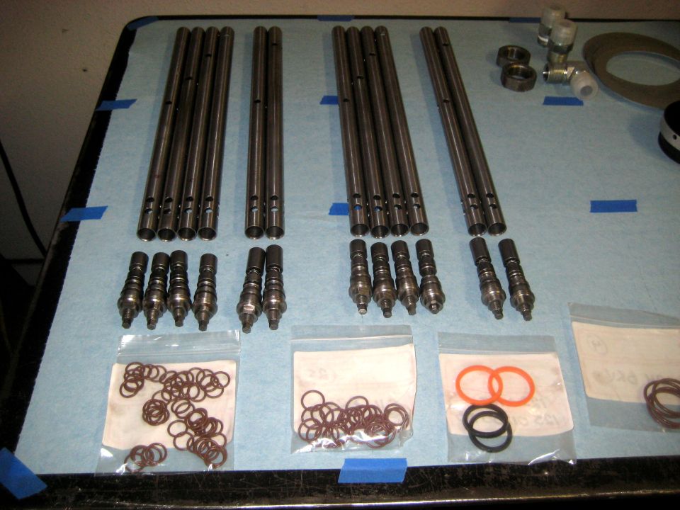 Valve train components including pushrods, lifters, and o-rings laid out on a blue cloth