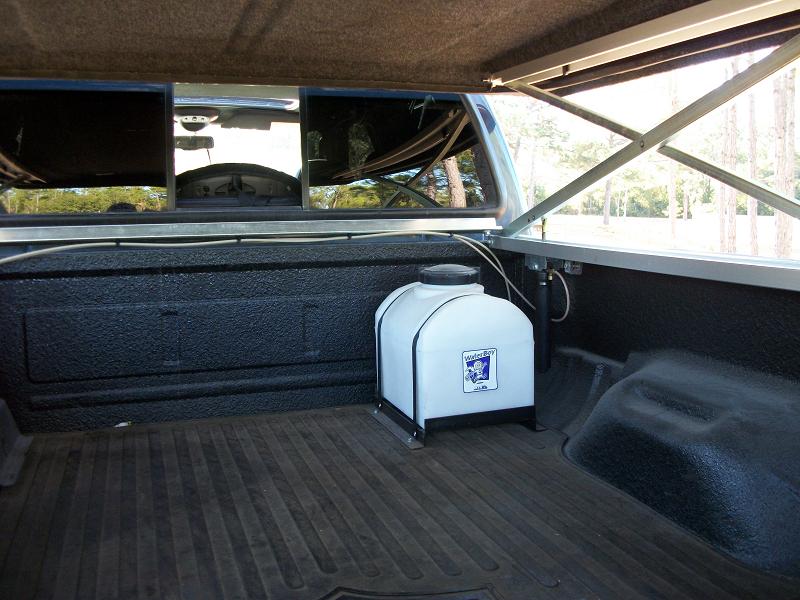 Truck bed interior showing a white water tank and the rear window