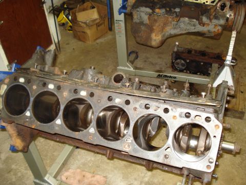 1991 Ford Bronco - Engine block with pistons and crankshaft visible, resting on a stand in a workshop.