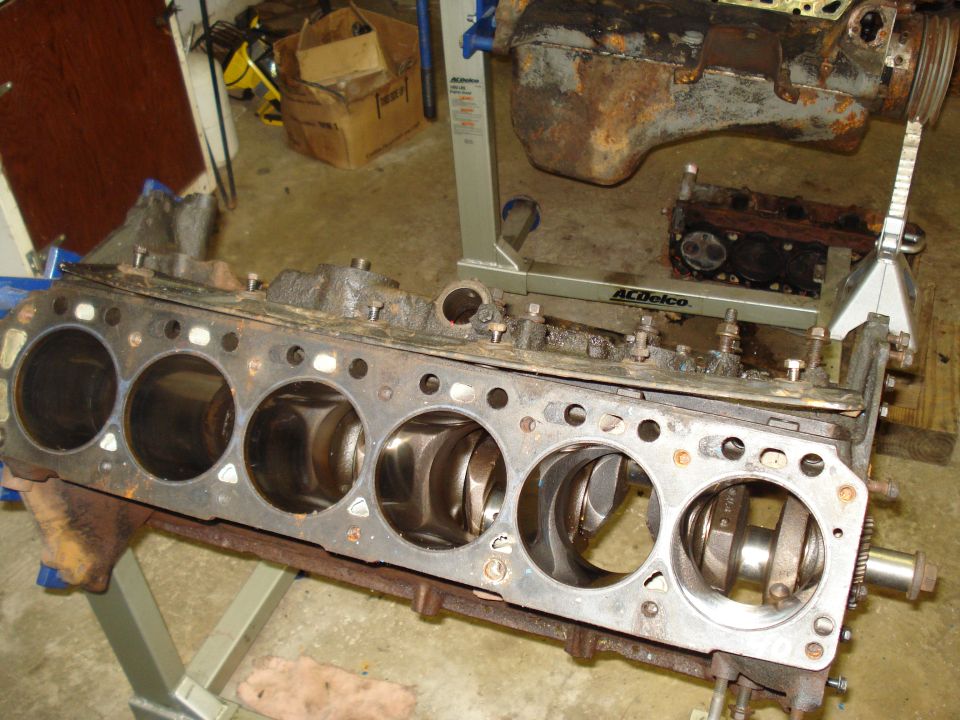 Engine block with pistons and crankshaft visible, on a stand