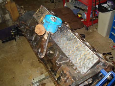 1991 Ford Bronco - A disassembled engine block sits on a stand, a blue distributor cap and a diamond plate cover.