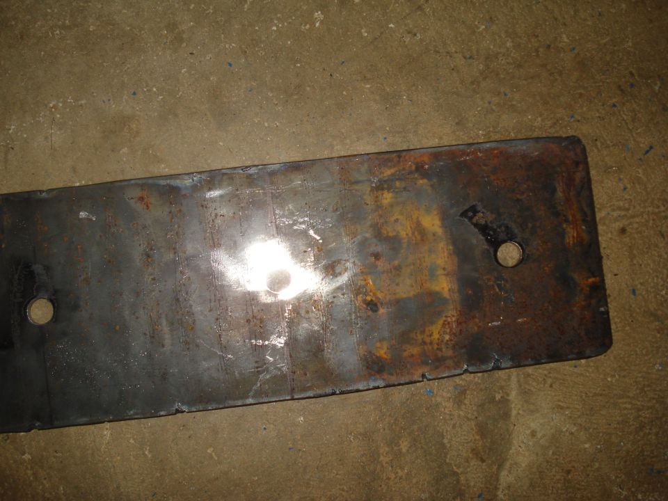 Rusty metal plate with two holes, on concrete floor