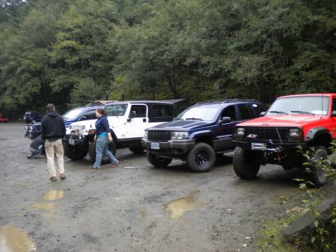 2005 Jeep Wrangler - A group of Jeeps, including a Wrangler and Grand Cherokee, are parked together on a dirt lot.