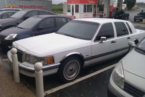 1991 Ford Crown Victoria - A white 1991 Lincoln Town Car is parked in a lot, with other vehicles visible.