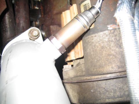 1996 Ford Bronco - Close-up view of an oxygen sensor connected to an exhaust pipe, with visible part numbers on the sensor.