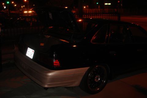 1993 Ford Taurus - Rear view of a 1993 Ford Taurus with its trunk open, showing custom wheels and two-tone paint.