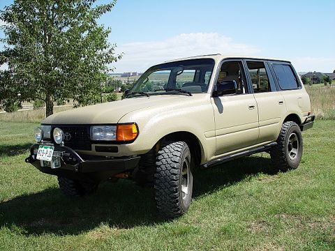 1978 Ford Bronco - This tan Toyota Land Cruiser FJ80 is shown from a three-quarter front angle on a grassy field.