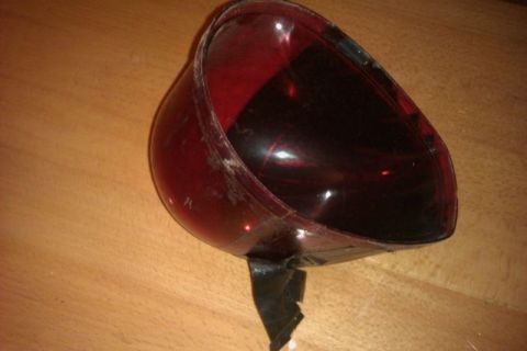 1991 Ford Crown Victoria - Close-up of a red plastic automotive part, likely a lens, with black tape affixed.