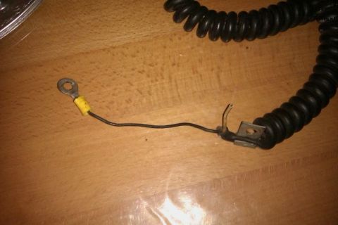1991 Ford Crown Victoria - A black coiled electrical cord with a ring terminal is shown on a wooden surface.