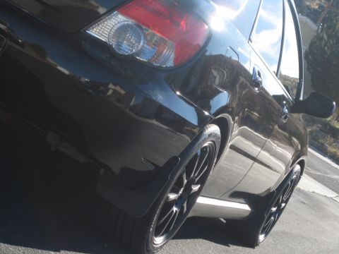 2005 Subaru Impreza - The rear of a black 2005 Subaru Impreza is shown from a low angle, highlighting the taillight and wheel.