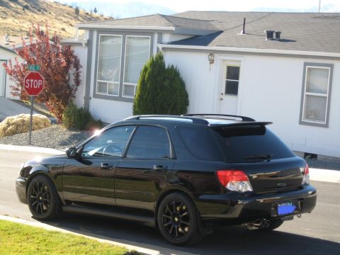 2005 Subaru Impreza - This black 2005 Subaru Impreza wagon is seen from a three-quarter front view, parked in front of a residential building.