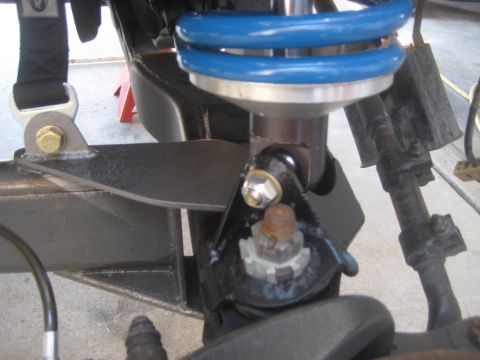 1996 Ford Bronco - Close-up view of a vehicle's front suspension system, highlighting a blue coilover shock absorber and associated mounting hardware.