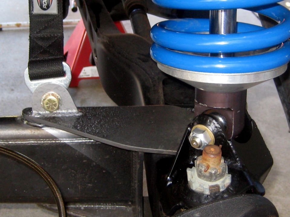 Close-up of a blue coilover shock absorber mounted to a black metal bracket with a black strap attached