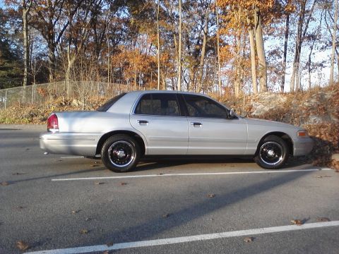 2000 Ford Crown Victoria - A silver sedan is parked in a lot during the fall. The vehicle appears to be a 2000 Ford Crown Victoria.