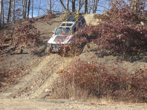 1991 Ford Bronco - A Hummer H3 navigates an off-road trail during daytime with autumn foliage.