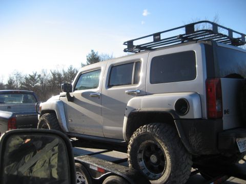 1991 Ford Bronco - A silver SUV with a roof rack is transported on a trailer, with another vehicle visible in the background.