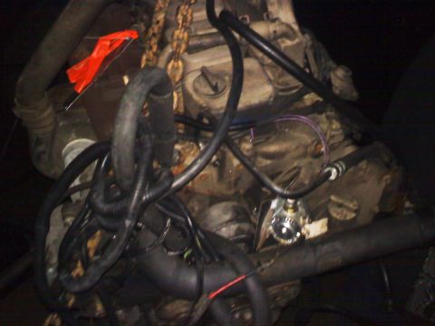 1990 Ford Bronco - Close-up view of an engine bay, showing various hoses, wiring, and a chain hoist. No specific vehicle year is identifiable.