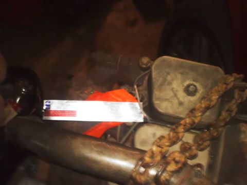 1990 Ford Bronco - Close-up of an engine part and chain, with a label attached.
