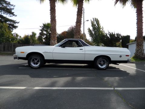 1973 Ford Ranchero - A white 1973 Ford Ranchero is seen from the side, parked between palm trees.