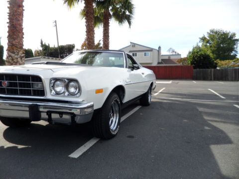 1973 Ford Ranchero - White 1973 Ford Ranchero parked in a lot with palm trees and houses in the background.