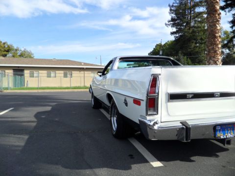 1973 Ford Ranchero - Rear view of a white 1973 Ford Ranchero pickup truck parked in a lot under a blue sky.