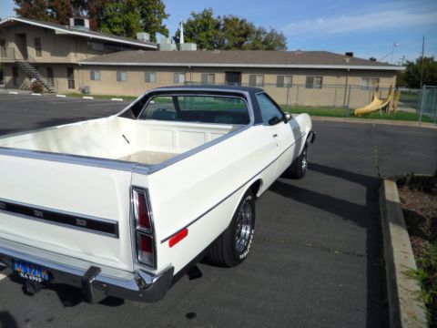 1973 Ford Ranchero - A white 1973 Ford Ranchero with a black vinyl top is parked outside a building.