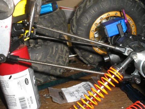 1994 Ford Escort - Close-up view of suspension components on a remote control car, including an orange coilover shock and a blue servo motor.