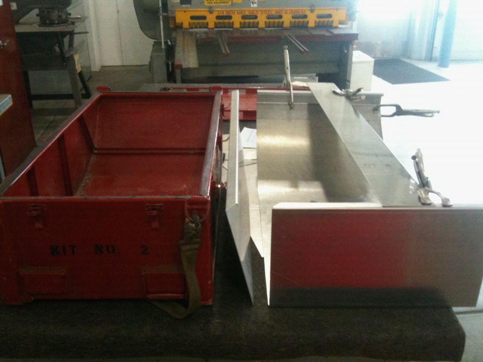 Red metal box labeled 'KIT NO. 2' next to a metal fabrication project