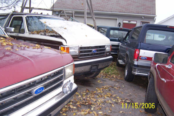 Ford Bronco parked next to other vehicles, hood up on one