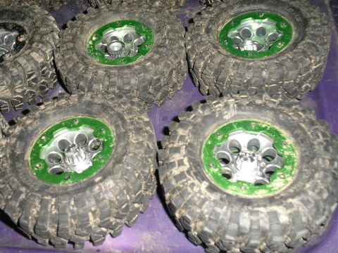 1994 Ford Escort - Multiple off-road tires with green rims and heavy tread are shown up close.