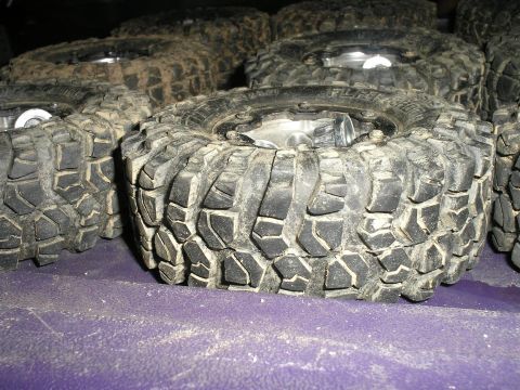 1994 Ford Escort - A collection of off-road tires, some appearing to be from a truck or SUV, are piled together.