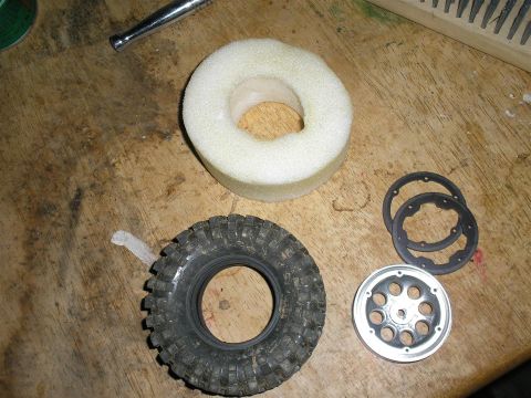 1994 Ford Escort - Parts for an RC car wheel assembly are laid out on a workbench.