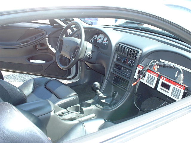1994 Ford Mustang interior showing dashboard, seats, and two red data loggers attached to the passenger side