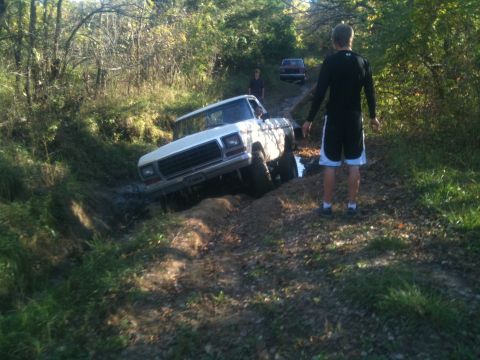 1978 Ford Bronco - A 1978 Ford F-Series truck is stuck in mud on a trail, with another vehicle visible further down the path.