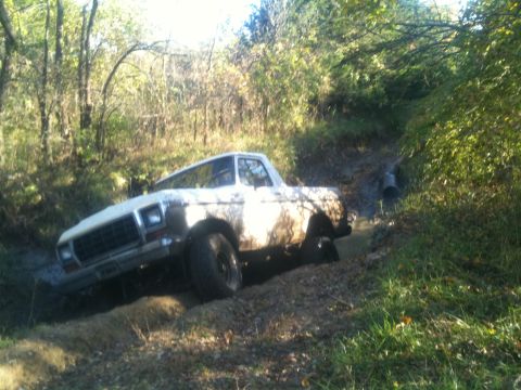 1978 Ford Bronco - A white 1978 Ford Bronco navigates a muddy, wooded path.