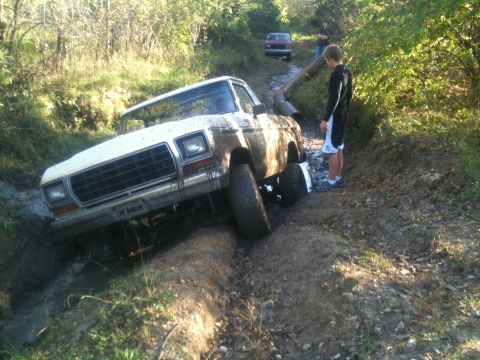1978 Ford Bronco - Muddy 1978 Ford F-Series pickup truck struggling off-road, with another vehicle in the distance.