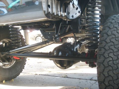 1986 Ford Bronco - The undercarriage of a vehicle is shown, with a focus on the suspension and drivetrain components.