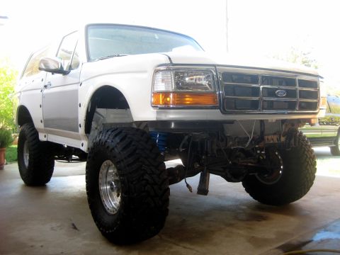 1996 Ford Bronco - This modified Ford Bronco, likely from the early to mid-1990s, is shown from the front with significant suspension and tire upgrades.