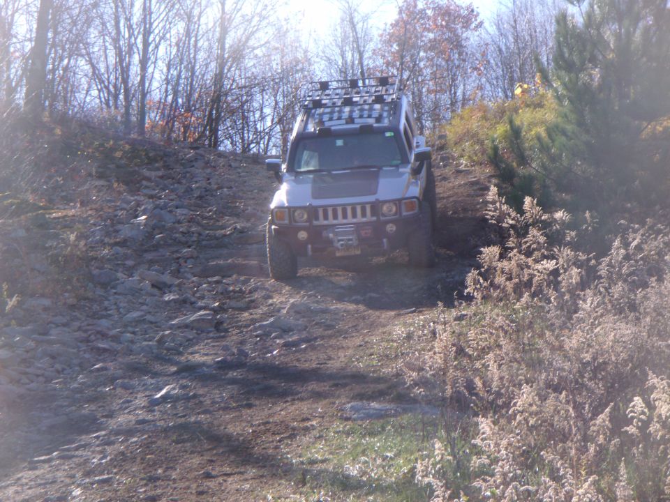 Hummer H2 driving up a rocky hill with trees around