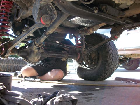 1969 Ford F-250 - A person works on the undercarriage of a vehicle, with another vehicle visible in the background.