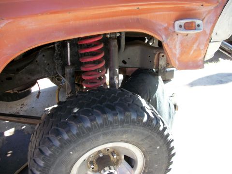 1969 Ford F-250 - Front suspension and tire of an orange truck, likely from the mid-1970s.