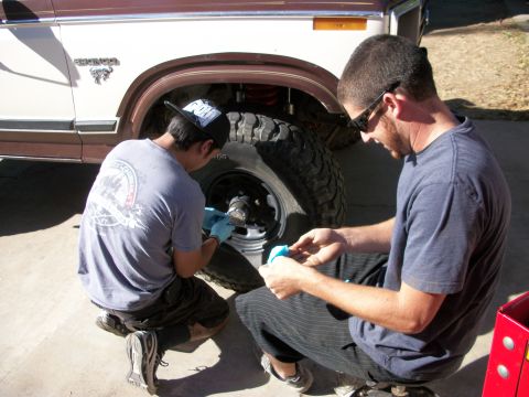 1969 Ford F-250 - Two men are performing maintenance on the wheel hub of a classic Ford Bronco.