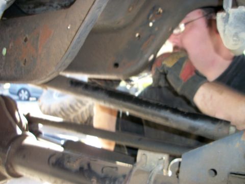 1969 Ford F-250 - A mechanic works on the underside of a truck, with a visible tire and frame components.