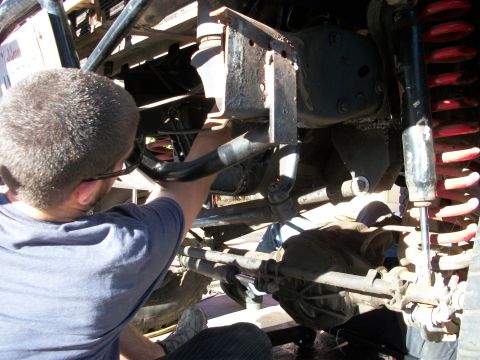 1969 Ford F-250 - A mechanic works on the undercarriage of a vehicle, focusing on the suspension system and differential.