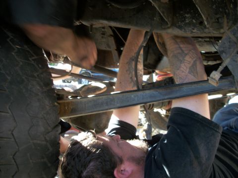 1969 Ford F-250 - Mechanics work on the underside of a vehicle, focusing on the chassis and suspension components.