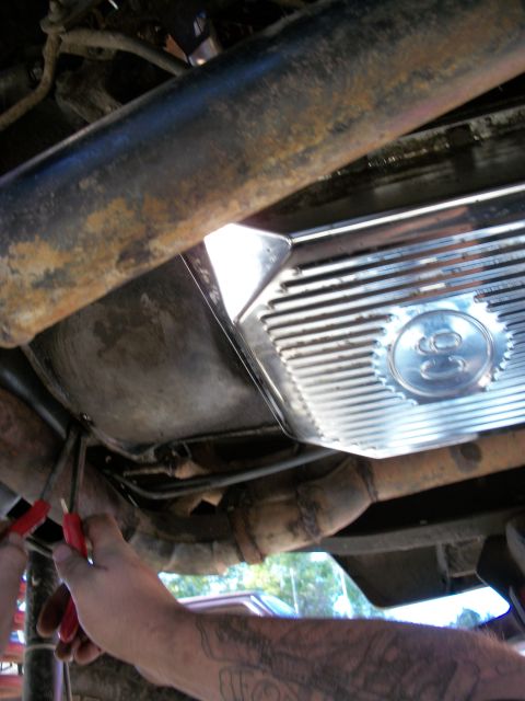1969 Ford F-250 - Underneath view of a vehicle's transmission pan and exhaust system during repair work.