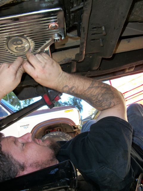 1969 Ford F-250 - Working on the transmission pan of a truck, with another truck in the background.