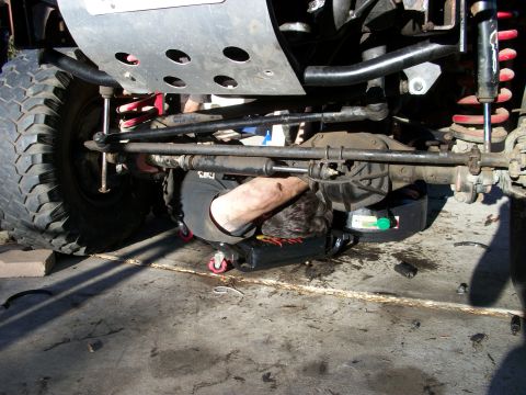 1969 Ford F-250 - Mechanic performing maintenance on the underside of a vehicle.